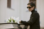 Widow Adjusting Flower on Coffin